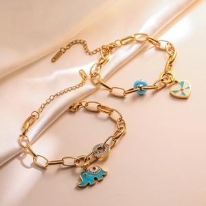 Detailed close-up of golden elephant and blue heart charm bracelets on white silk fabric
