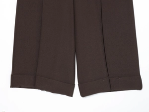 Dettaglio del risvolto dei pantaloni marrone scuro con trama saia e cuciture precise