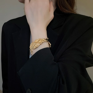 Detailed view of golden irregular lava texture bracelet worn against a black suit