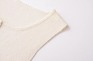 Détail du gilet en maille crème montrant la texture fine et les finitions de couture