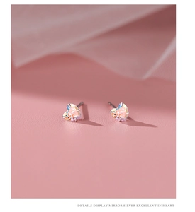 Macro detail of heart-shaped silver earrings featuring iridescent aurora crystals