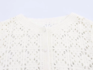Close-up of cream white crochet cardigan featuring hollow-out knit texture and button closure
