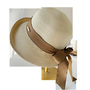Détail d'un chapeau de paille avec ruban marron sur un support en métal doré