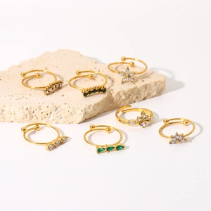 Detail of 18K gold plated rings with white and green zircons on beige stones