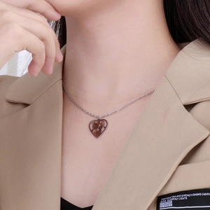 Detailed close-up of a silver heart pendant necklace featuring mother and child silhouette