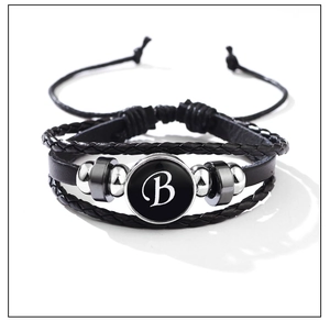 Macro shot of black leather multi-layer bracelet featuring a circular letter B pendant