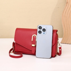Detail of red leather crossbody phone bag with gold hardware and dual zipper compartments