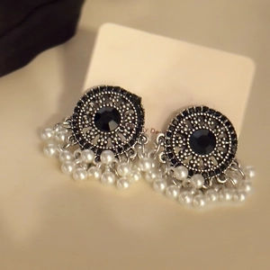 Dettaglio di orecchini vintage con pietra nera sfaccettata e nappe di perle bianche