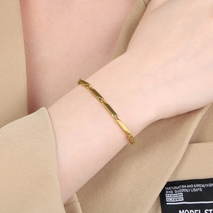 Detail of minimalist gold chain bracelet with polished bamboo joints on a model