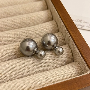 Macro detail of grey double-sided pearl earrings with silver posts in a jewelry box