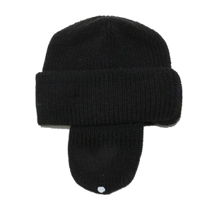 Detail of black chunky knit earflap hat with soft texture and white decorative button