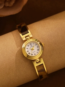 Detail of a vintage tortoise gold watch with a Roman numeral dial and chain bracelet