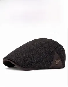 Detailed view of dark gray woolen newsboy hat featuring vintage triangular metal badge