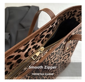 Close-up of leopard print tote bag featuring a smooth gold metal zipper and brown leather trim