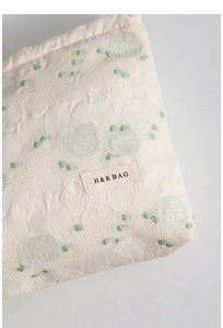 Detailed macro view of beige jacquard fabric with rose floral embroidery and H&R BAG logo tag