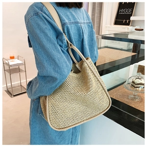 Detail of hand-woven straw tote with leather trim shown carried on model shoulder