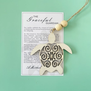 Detail of wooden sea turtle charm with mother-themed card on green background