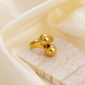 Close-up of a double sphere gold ring on a stone base with silk background texture