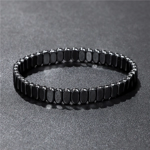 Macro detail of polished black hematite cylindrical beads on an elastic bracelet