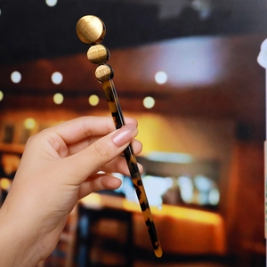 Macro shot of tortoiseshell acetate hair stick featuring three golden metal disk ornaments