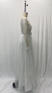 Vue latérale d'une robe de mariée en dentelle blanche avec manches longues et nœud