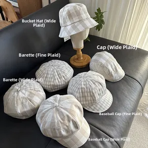 Close-up of linen plaid hats including bucket and beret styles on a leather surface