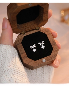 Close-up of S999 silver bowknot earrings with zircon in a walnut wood jewelry box