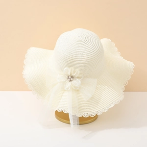 Gros plan sur un chapeau de paille blanc avec bord en dentelle et perles florales