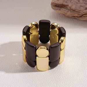 Detailed close-up of geometric gold and dark brown acrylic link bracelet on neutral base