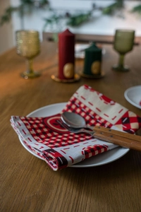 Detail of Christmas buffalo plaid napkin with rustic wooden handle cutlery on white plate