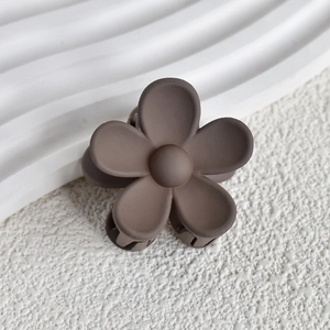 Macro detail of a matte coffee brown flower hair claw clip with a frosted resin texture