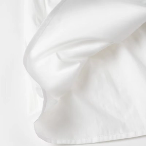 Detailed close-up of white fabric texture showing fine stitching and soft draping
