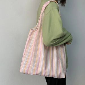 Grand sac cabas en toile à rayures roses et oranges, porté épaule par un mannequin, spacieux
