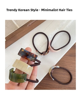 Detail of tortoise shell acetate hair ties with gold handmade lettering and elastic bands