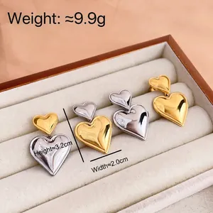 Two-tone heart-shaped titanium steel earrings in gold and silver finish in a jewelry box