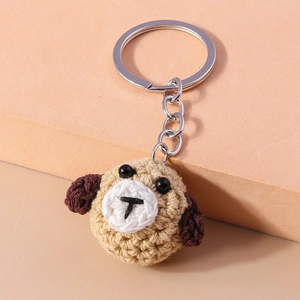 Close-up of handmade crochet dog keychain featuring beige yarn and brown ears with metal ring