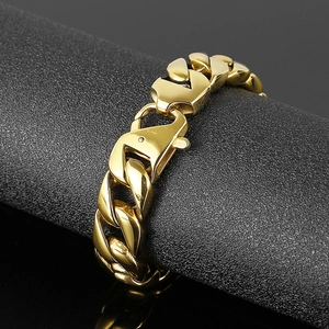 Detail of a large gold Cuban link bracelet with lobster clasp on a black textured stand