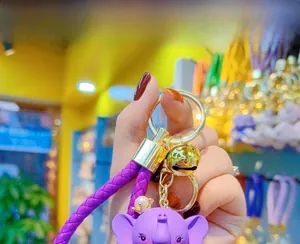 Detail view of purple resin elephant keychain with woven strap and golden bell charm