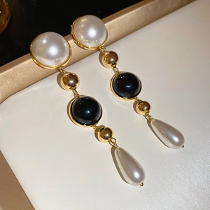 Macro detail of 18k gold plated drop earrings with white pearls and black beads