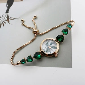 Detail of gold quartz watch with green heart gemstones and marble pattern dial