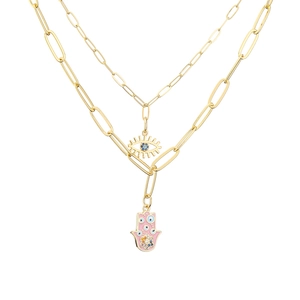 Close-up of double-layer gold necklace with Hamsa hand and evil eye charms with gems