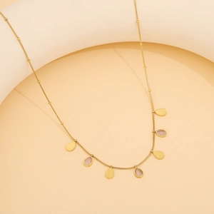 Détail du collier doré avec pierre œil de chat rose et pendentifs en forme de goutte