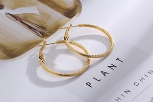 Detailed view of large gold hoop earrings featuring a vintage twisted rope texture design