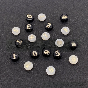 Vista piana di perline tonde in conchiglia da 8mm con numeri dorati per gioielli fai da te