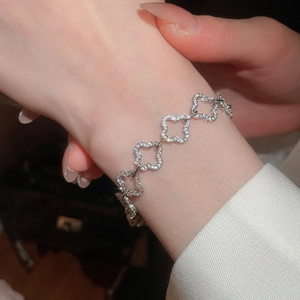 Close-up of sparkling silver clover bracelet with cubic zirconia on a female wrist
