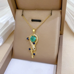 Macro shot of gold pendant with square emerald stone and blue crystal accents