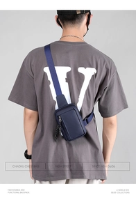 Detail view of navy blue water-resistant chest bag on a model wearing a grey t-shirt