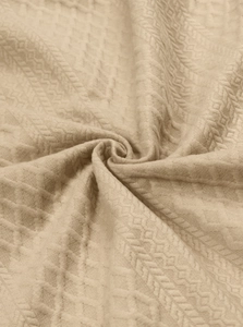 Detailed macro view of beige jacquard waffle texture fabric with elegant spiral drape
