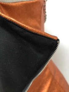Detailaufnahme von orangefarbenem Metallgewebe mit schwarzem Kontrast und Metallreißverschluss