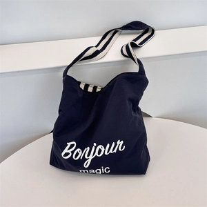 Detail of navy canvas tote featuring Bonjour print and blue striped shoulder strap
